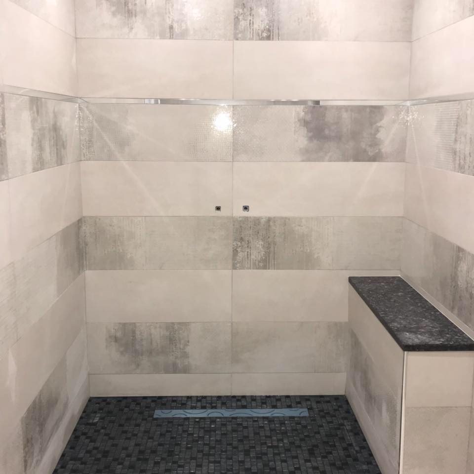 Douche à l'italienne au sol en mosaïque noire et banc en granit